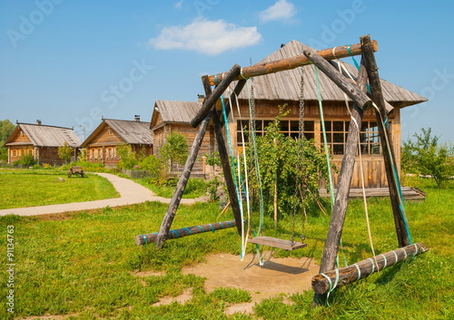 Wooden swing on the lawn in the Russian village