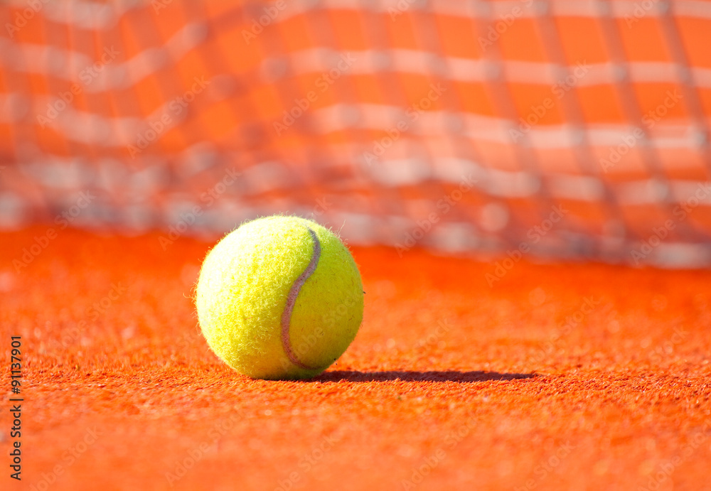 Tennis ball on a orange hard court