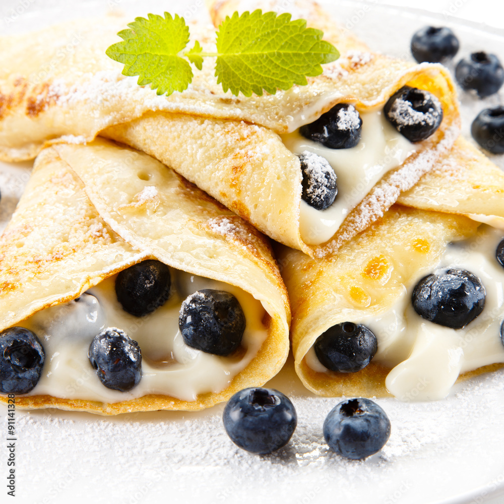 Crepes with blueberries and cream on white background Crepes with blueberries and cream on white background