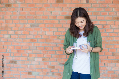 Happy asian woman relaxing outdoor and reading book photo