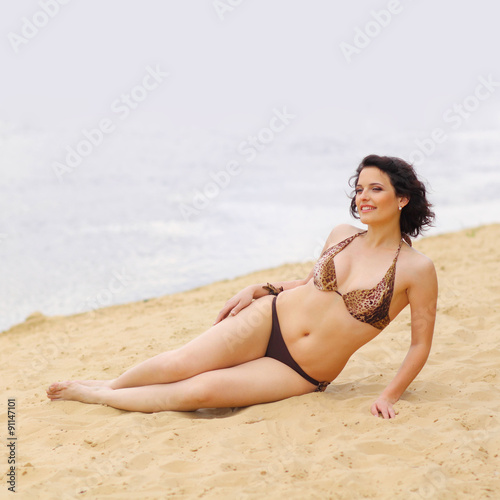 full girl posing on the beach in a bikini. plump woman sunbathing on the beach