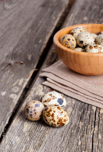 quail eggs in a wooden bowl on a gray background