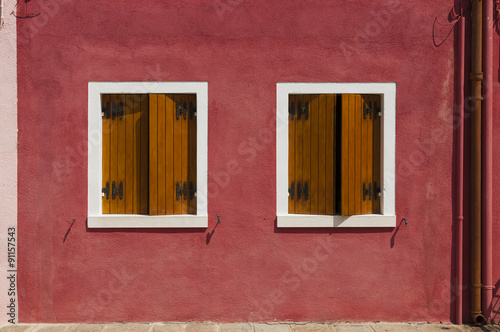 Red wall  of Burano Island with two windows, Venice, Italy