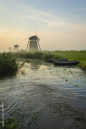 Foggy windmills on a dike