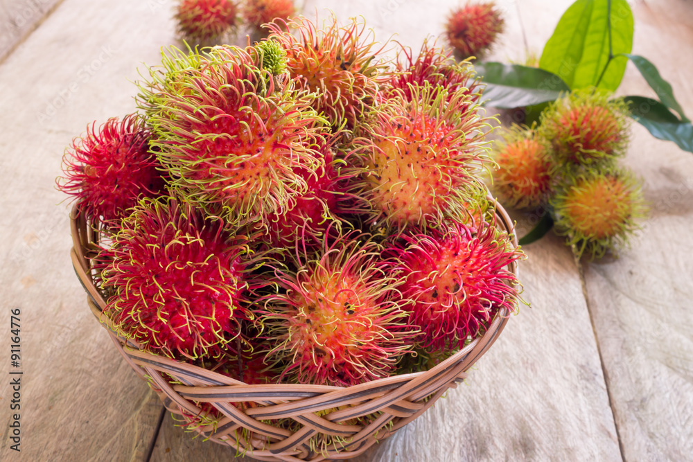 Fresh red rambutan sweet delicious fruit in basket on wood table. Tropical fruit tree, native to South - East Asia , cultivated in many countries in the region. Fresh red rambutan sweet delicious fruit in basket on wood table. Tropical fruit tree, native to South - East Asia , cultivated in many countries in the region.