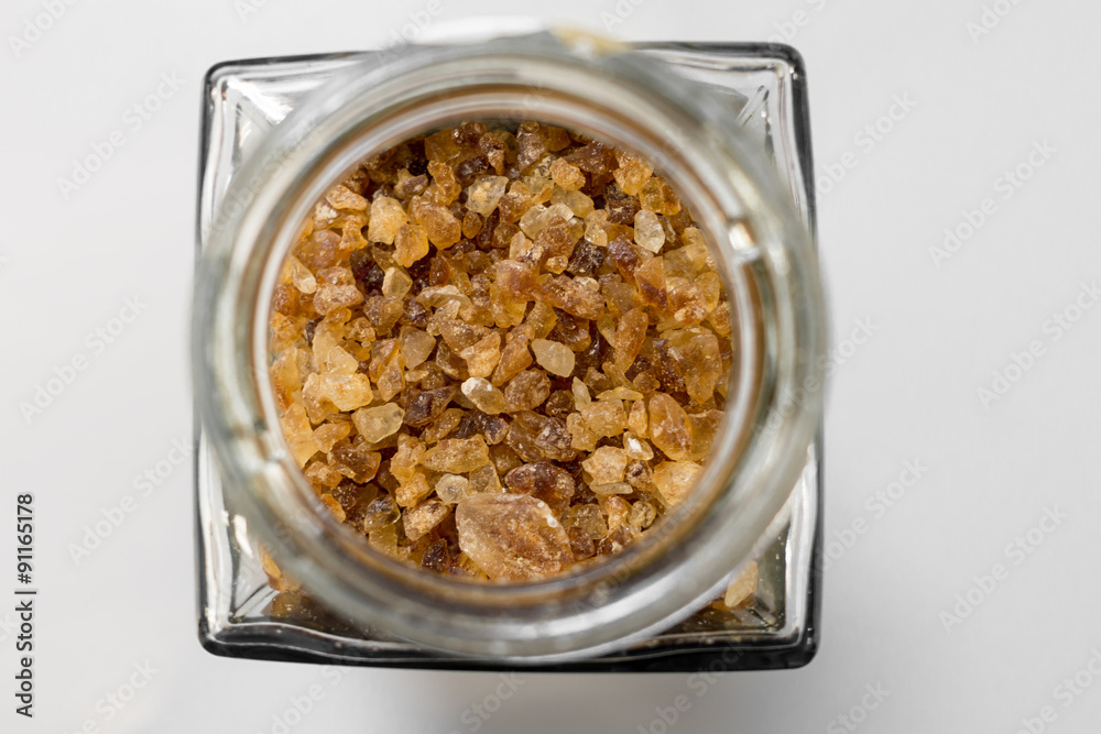 Brown rock candy crystals sugar in glass bottle on white background Brown rock candy crystals sugar in glass bottle on white background