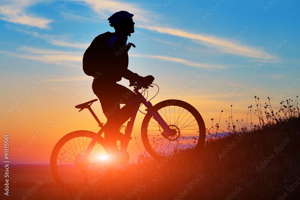 Fototapeta premium Silhouette of a biker and bicycle on sunset background.
