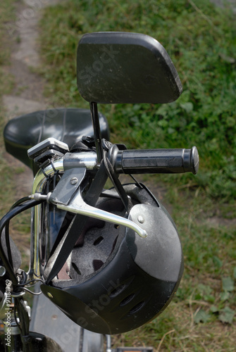 Gray and black helmet hanging on the moped helm