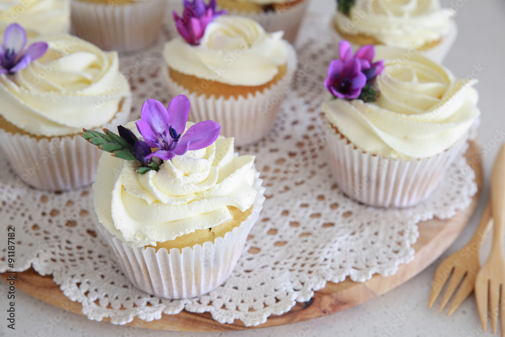 Homemade purple freesia flowers on vanilla cupcakes with whipped Homemade purple freesia flowers on vanilla cupcakes with whipped
