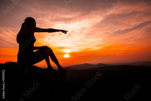 Silhouette of woman watching sunset and pointing