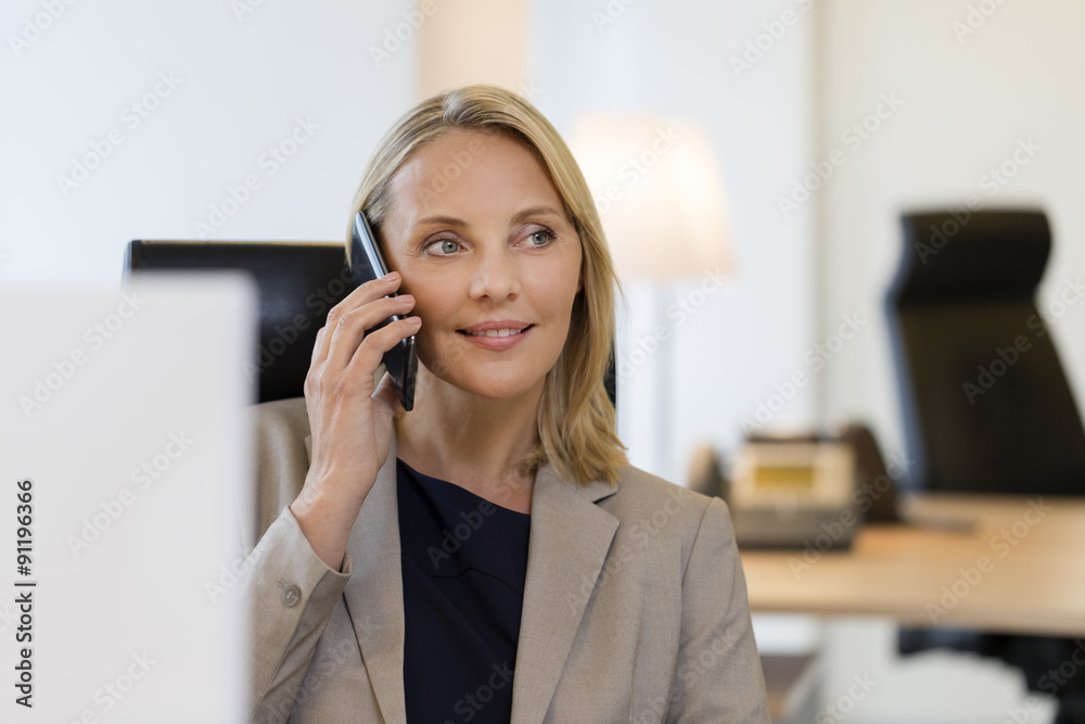Cheerful business woman on mobile phone at office