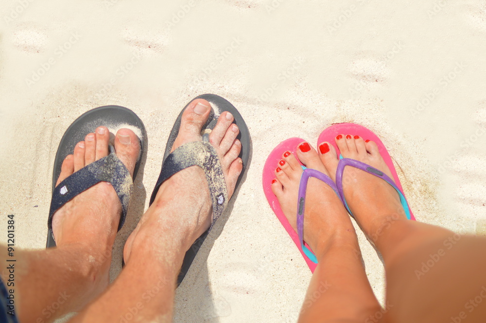 Fototapeta premium Couple walking with flip flops on the beach