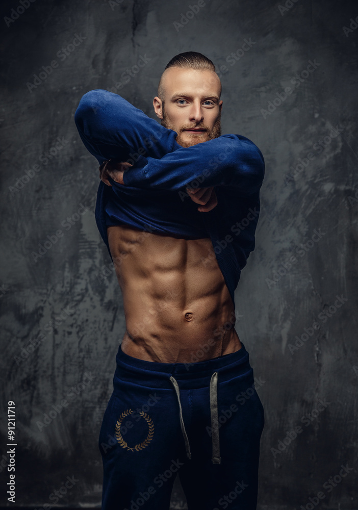 Fototapeta premium Muscular guy with beard putting out his sport shirt.