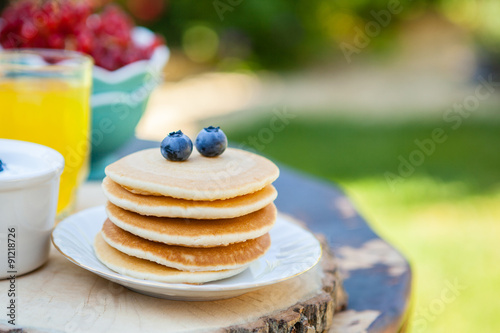 Breakfast in the garden: pancakes with yoghurt and berries on a rustic table