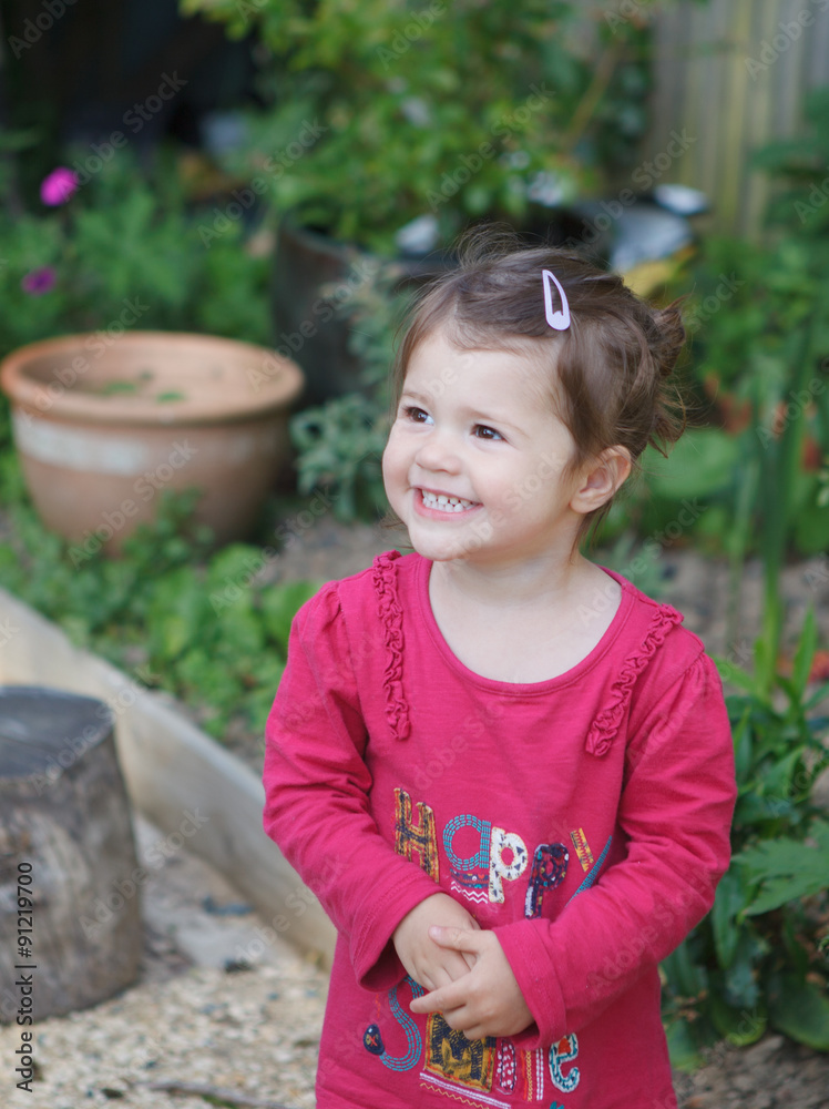 Fototapeta premium A little girl in the garden laughing