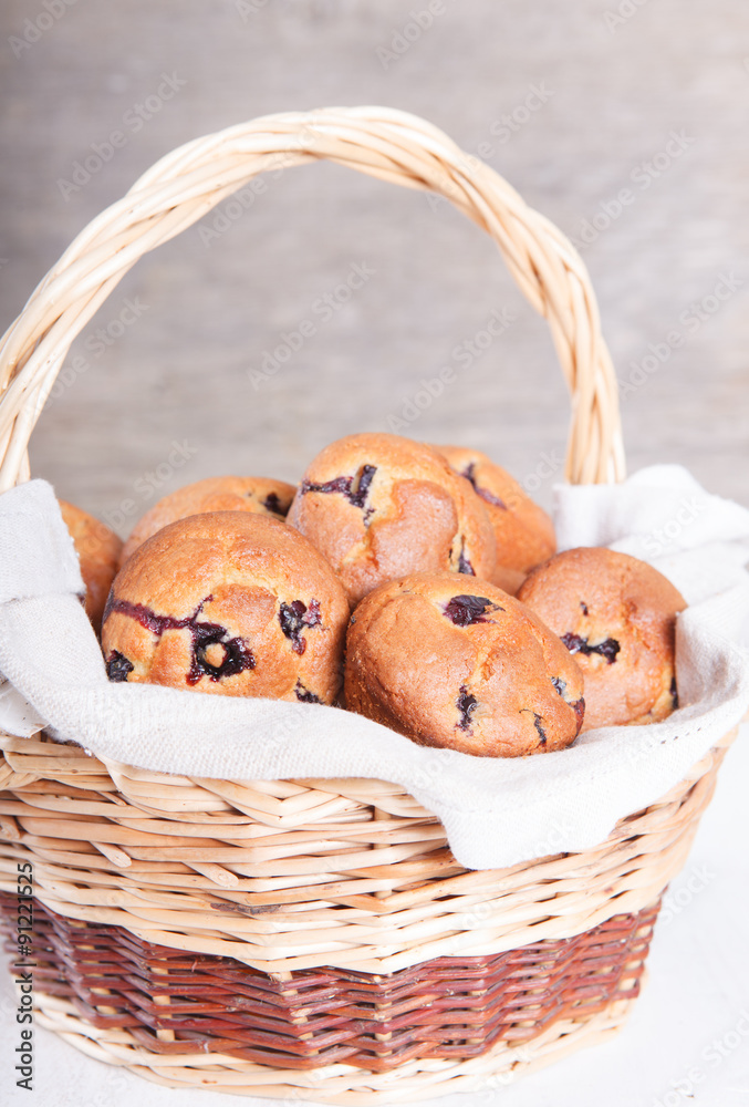 Bblueberry muffins in the wicker basket on the white wooden tabl