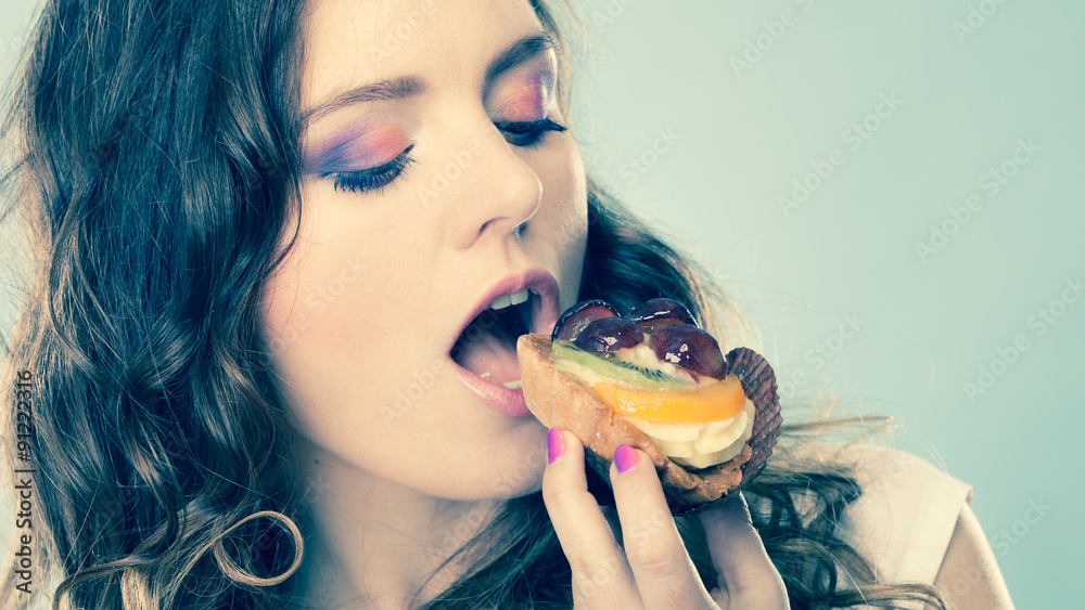 Cute girl holds fruit cake in hand on blue Cute girl holds fruit cake in hand on blue