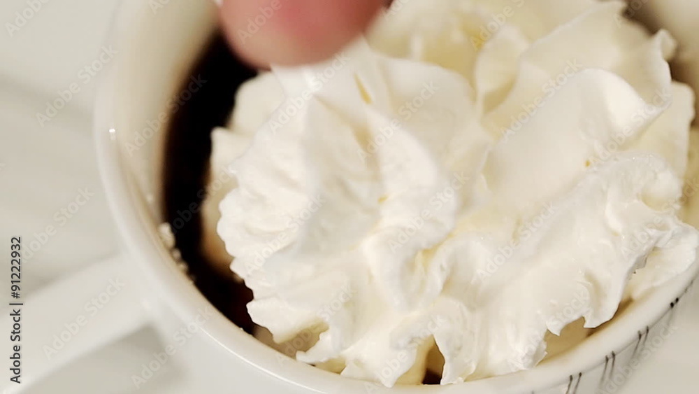 Pouring whipped cream over a coffee
