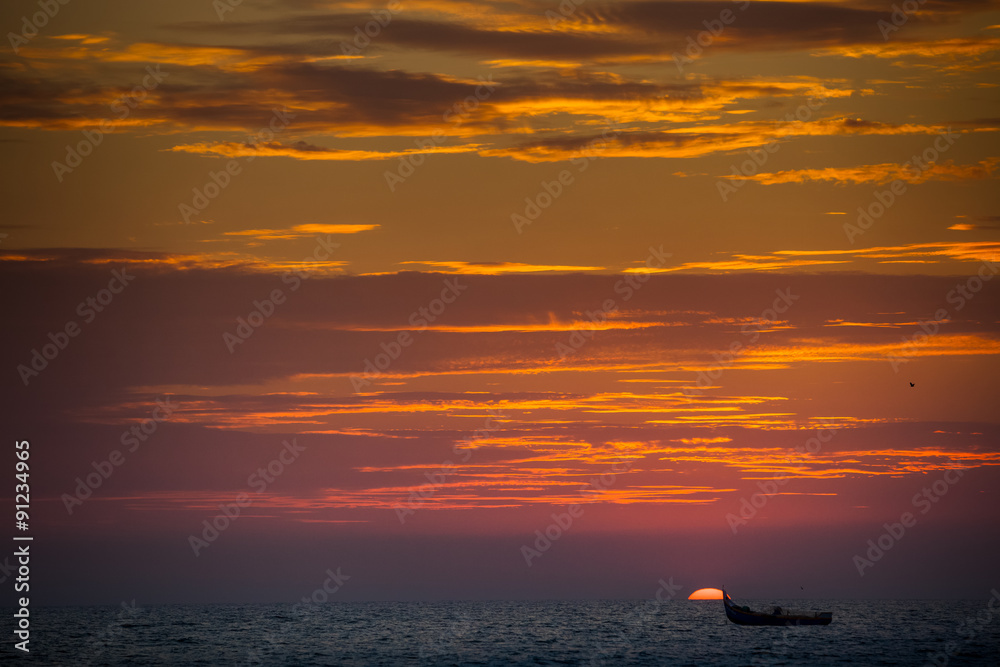 view of sea boat against large sun disk rising from behind sea