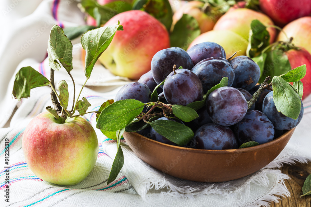 Ripe apple and plums in ceramic bowl Ripe apple and plums in ceramic bowl