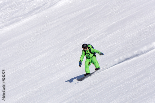 Snowboarder going down the slope at ski resort.