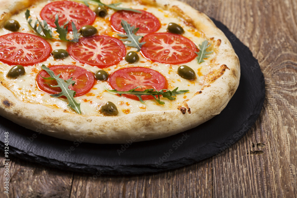 Pizza vegetarian on plate on stone black try with fresh tomatoes