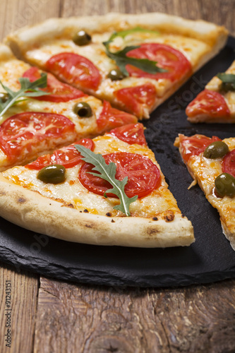 Pizza vegetarian on plate on stone black try with fresh tomatoes