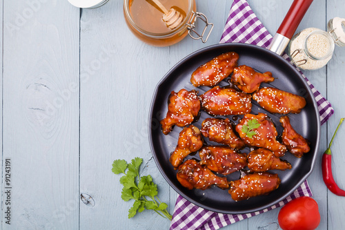 Baked chicken wings in honey sauce sprinkled with sesame seeds. photo