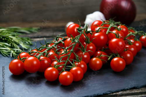 Fresh Tomatoes and Green Vegetables. Onion, Rosemary, garlic on on a stone board