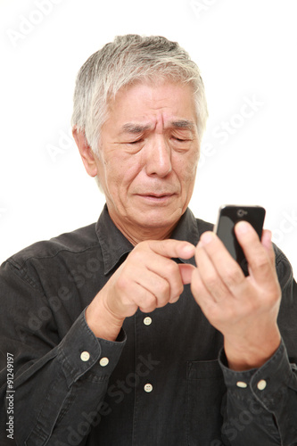 senior Japanese man using smart phone looking confused