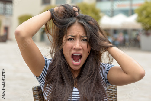 Upset frantic young woman tearing at her hair