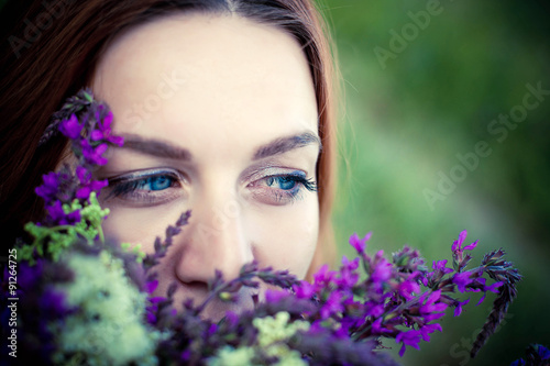 Romantic red-haired young woman smelling a flower on a flower © emaria