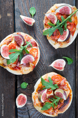 Small pizza with salami, arugula and fresh figs