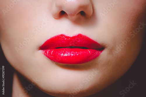 Dramatic lips makeup in red colors on dark indoor background