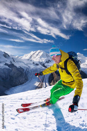 Narciarz zjazd na nartach w wysokich górach przeciw błękitne niebo