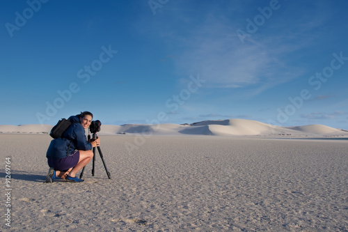 Female photographer taking landscape photo of sand dunes