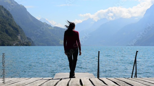 Woman sitting in lotus position and meditating on the lake. The breeze shakes her long hair.