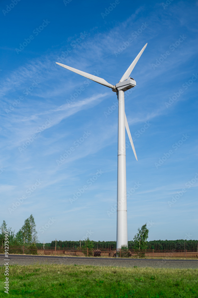 Windmills for electric power production on the green grass. land