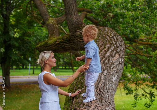 Mother playing with her child on tree in a park. © Fxquadro