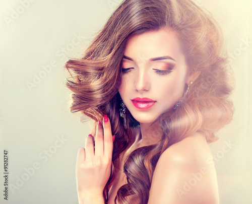 Beautiful model brunette with long curled hair and jewelry earrings 