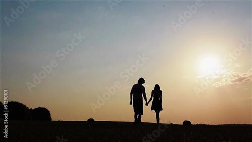 Wallpaper Mural Young slim and playful silhouette couple standing and walking in a field full of haystacks at sunset Torontodigital.ca