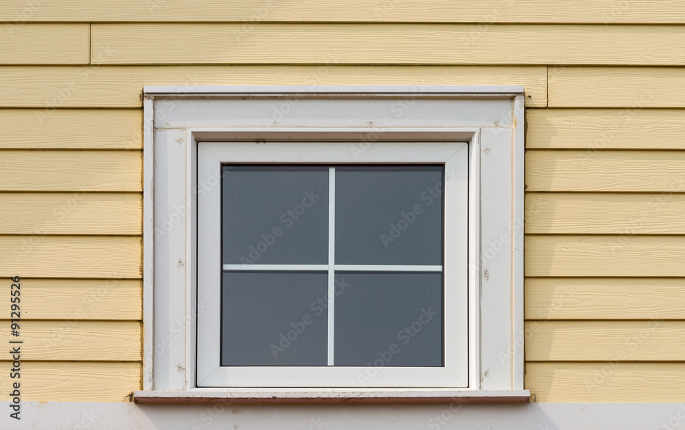 Small square window on a siding covered wall