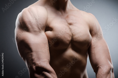 Muscular man posing in dark studio