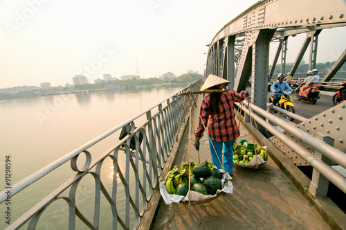 The street vendor carrying her fruit across Trang Tien bridge, Hue city, Vietnam