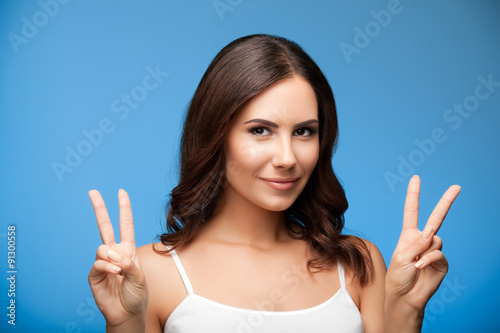 woman showing two fingers or victory gesture, on blue