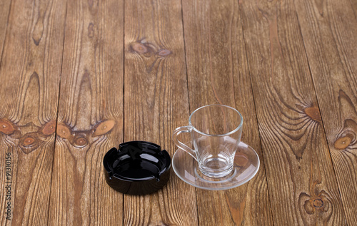 Empty cup with dish and ashtray on wooden texture