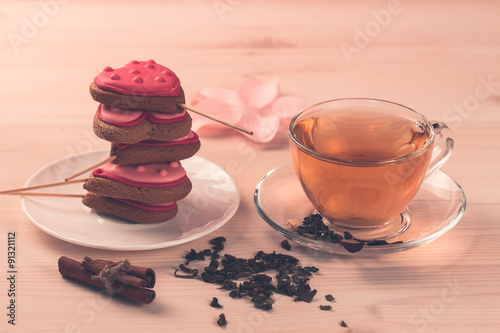 delicious fresh cookies in the shape of a heart on a white plate on wooden background. Cup of green tea. Breakfast