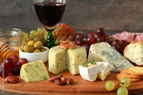 Glass of red wine with various types of cheese, fruits and appetizers