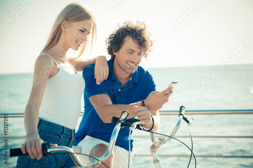 Man and woman on bicycle using smartphone together © Drobot Dean