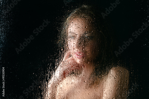 Сексуальная девушка за мокрым стеклом